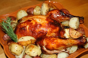 Ψητό κοτόπουλο με πατάτες σε ξύλινη σανίδα