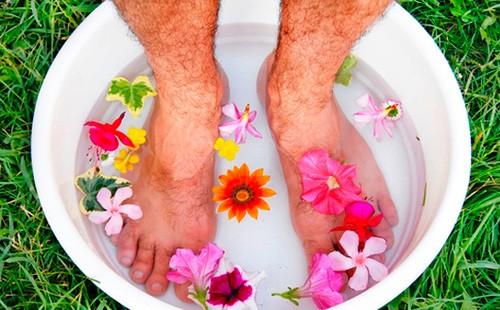 Gambe da uomo in una vasca con acqua e fiori