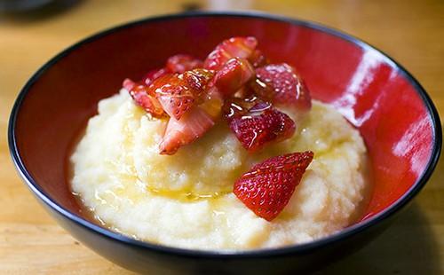 Porridge con fragole tritate in un piatto rosso scuro
