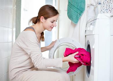 Жена поставя червен пуловер в пералнята