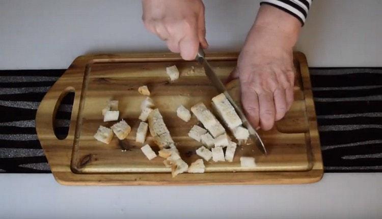 Taglia a dadini alcune fette di pane per fare i cracker.