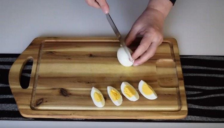 Wir schneiden die gekochten Eier in Viertel.