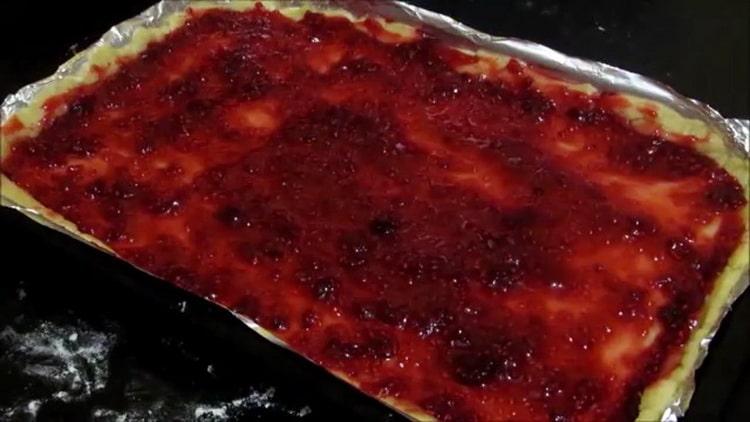 Um Shortbread-Kekse mit Marmelade zuzubereiten, legen Sie den Teig auf ein Backblech und die Marmelade auf einen Teig