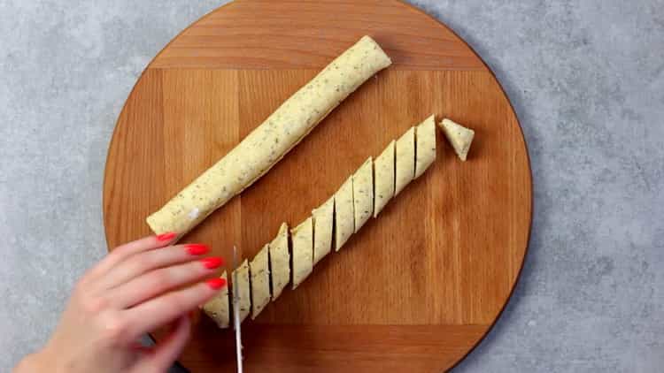 Per fare i biscotti con formaggio fuso arrotolare un rotolo di pasta