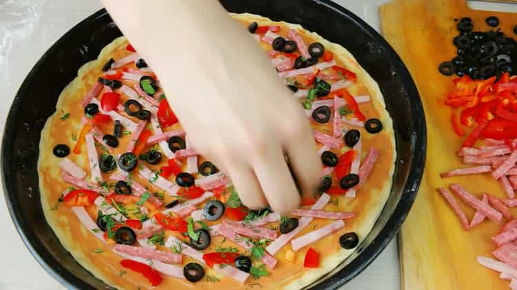 Um eine hefefreie Pizza zuzubereiten, geben Sie die Füllung auf den Teig.
