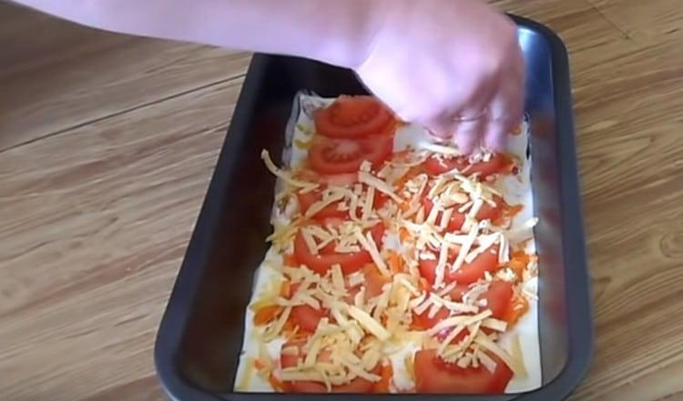 Dann die Tomatenstücke verteilen und das Gericht mit Käse bestreuen.