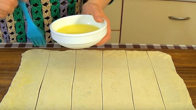 Fetten Sie jeden Teigstreifen mit geschmolzener Butter ein.