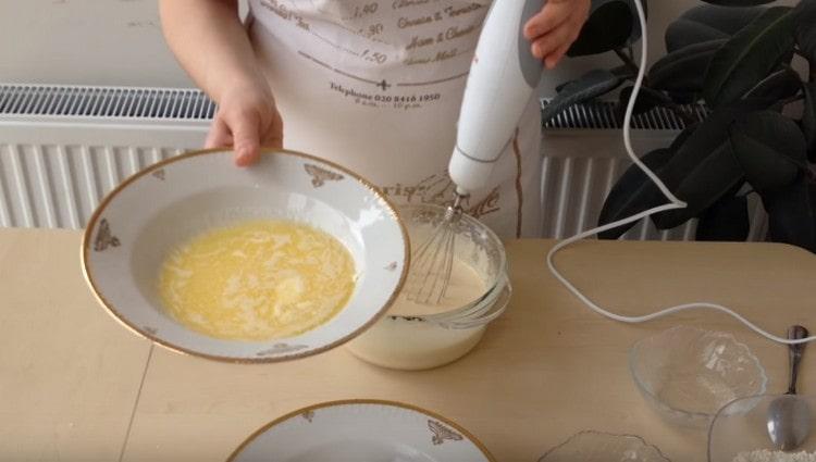 Führe das Schlagen fort und gib geschmolzene Butter zu der Eimasse.