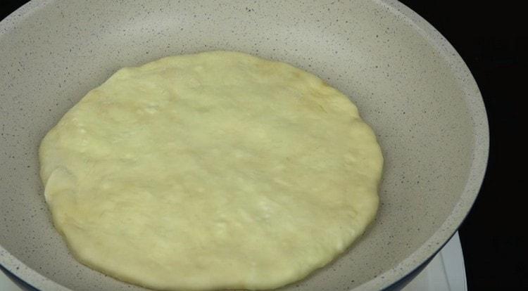 Fry khachapuri na may keso sa isang dry pan.