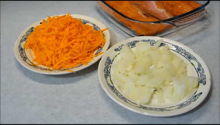 Schneiden Sie Zwiebeln und Karotten für die Herstellung von rosa Lachs