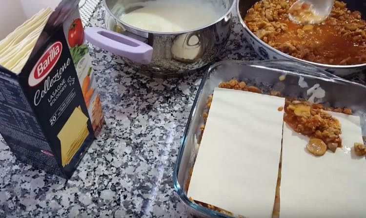 Alternare fogli di lasagne e salse, raccogliendo un piatto.
