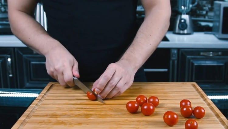 Нарежете чери доматите наполовина.