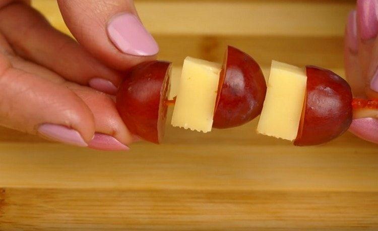 Abwechselnd einen Spieß mit Trauben und Käsestücken aufsetzen.